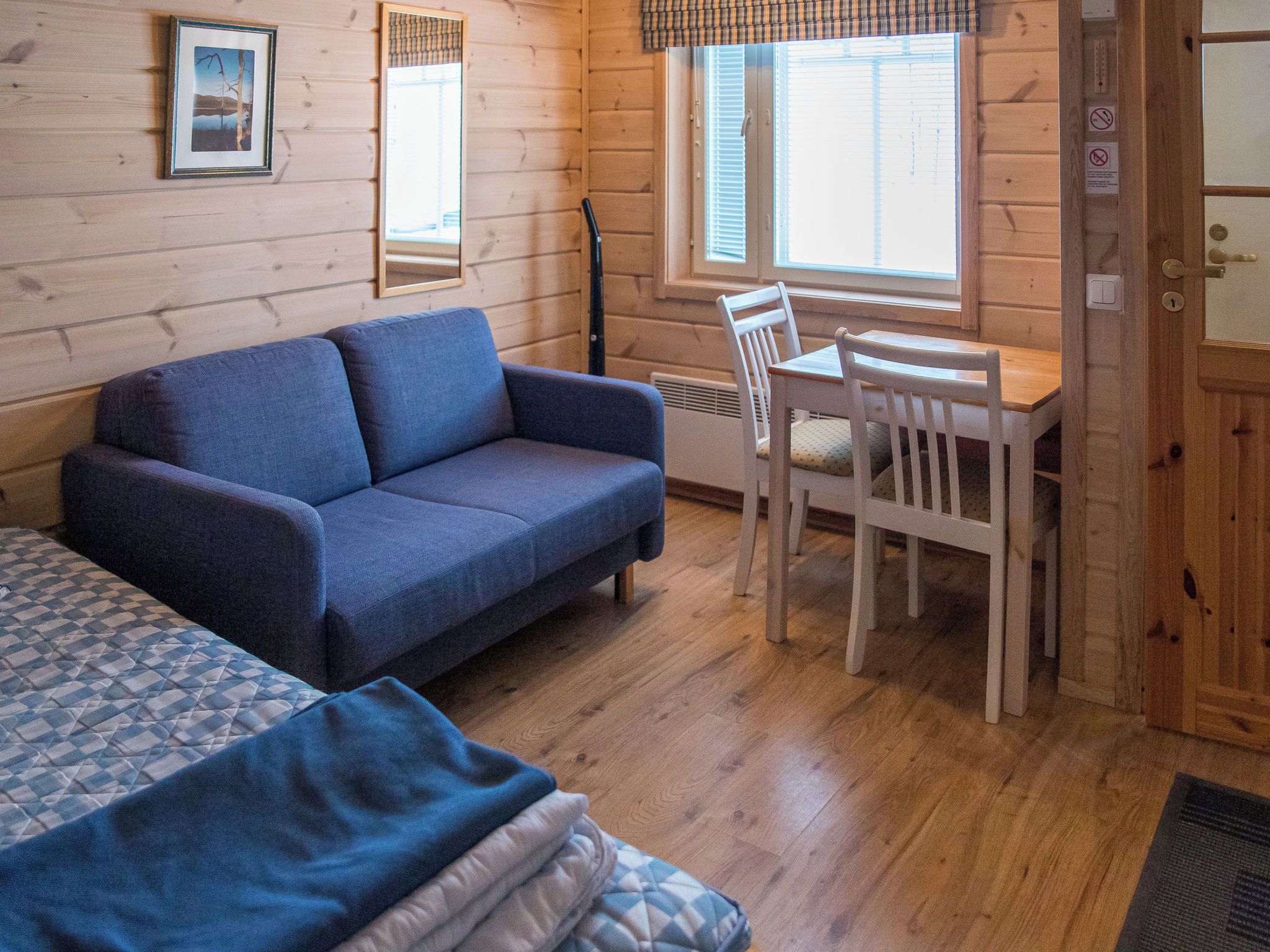Une pièce confortable avec un canapé, une table à manger et des chaises, ainsi qu’une fenêtre avec des stores.