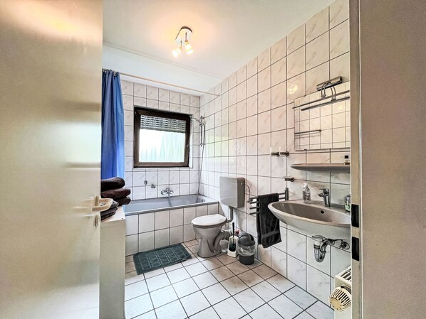 Une salle de bain avec des toilettes, un lavabo et une baignoire.