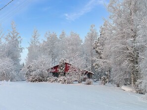 Un paisaje nevado con un edificio rojo, rodeado de árboles.