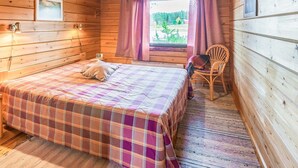 Een gezellig houten kamer met een bed, een stoel en een raam met gordijnen.
