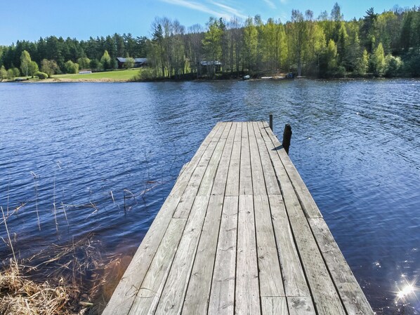 A wooden dock extending into a calm lake with a forested shoreline in the background.