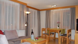 Un salon avec un canapé, une table à manger et des chaises, un lampadaire et un téléviseur.