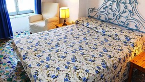 Une chambre d’hôtel avec un lit, une chaise, une lampe et une fenêtre.