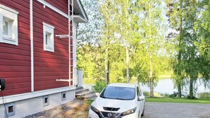 Valkoinen auto oli pysäköitynä punaisen rakennuksen eteen, ja rakennuksen edessä oli sorapäällysteinen ajotie.