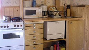 Een keuken met een fornuis, magnetron en houten kastjes.