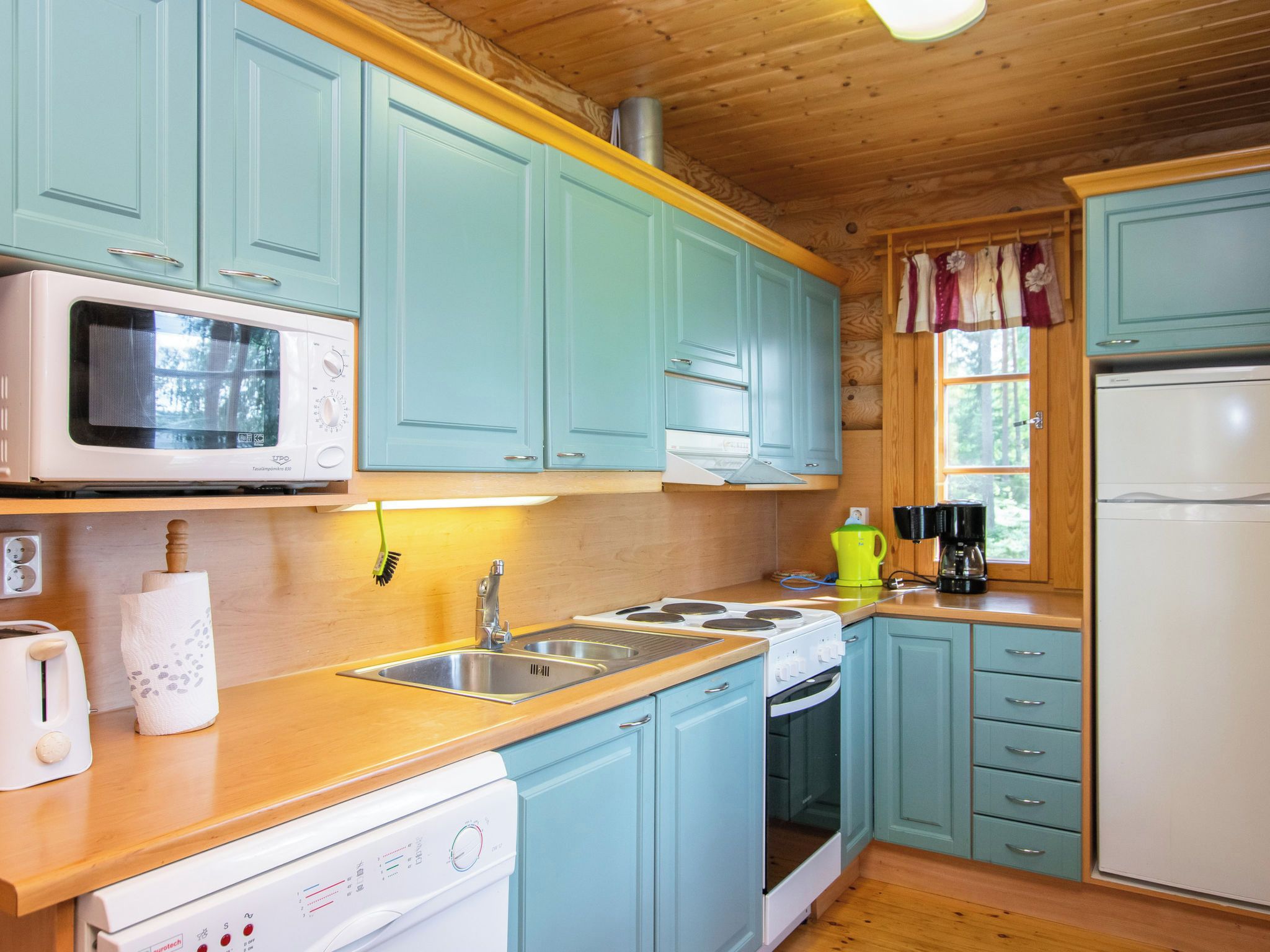 Una cocina con armarios azul claro, un microondas, una estufa, un fregadero y un refrigerador.