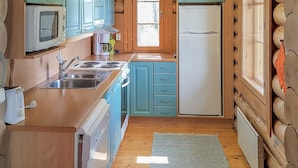 A compact kitchen with teal cabinets, a white refrigerator, and a coffee maker. - Männikkö by Interhome (Sulkava)