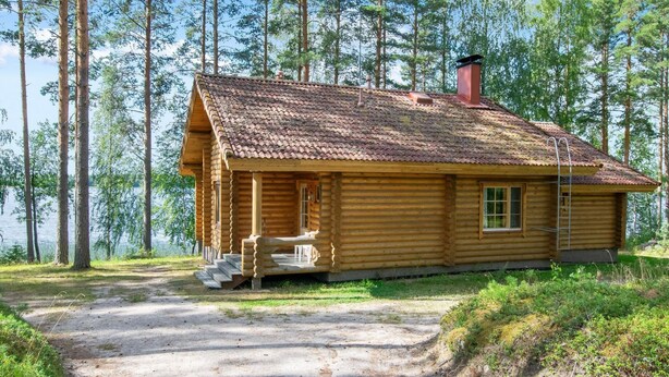 A log cabin with a dirt path leading to it, surrounded by trees and a body of water. - Männikkö by Interhome (Sulkava)