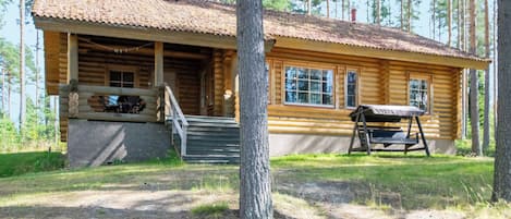 A log cabin with a porch, a bench, and a staircase leading to the entrance.