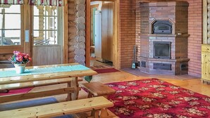 A rustic interior with wooden furniture, a fireplace, and a red patterned rug. - Männikkö by Interhome (Sulkava)