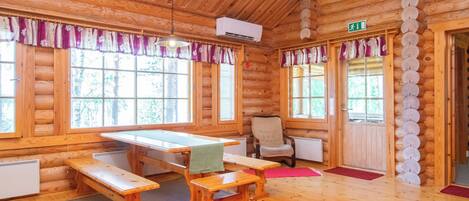 A log cabin interior with a dining table, benches, a chair, and a red carpet.