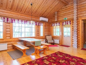 A log cabin interior with a dining table, benches, a chair, and a red carpet. - Männikkö by Interhome (Sulkava)