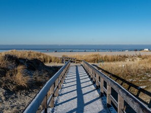A wooden boardwalk leading to a beach with a clear sky. - Am Deich by Interhome (Norddeich)