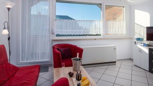 Una habitación moderna con un sofá rojo, una mesa de comedor con una botella de champán y un televisor sobre un mueble.