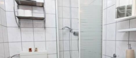 A bathroom with a toilet, a shower, and a sink.