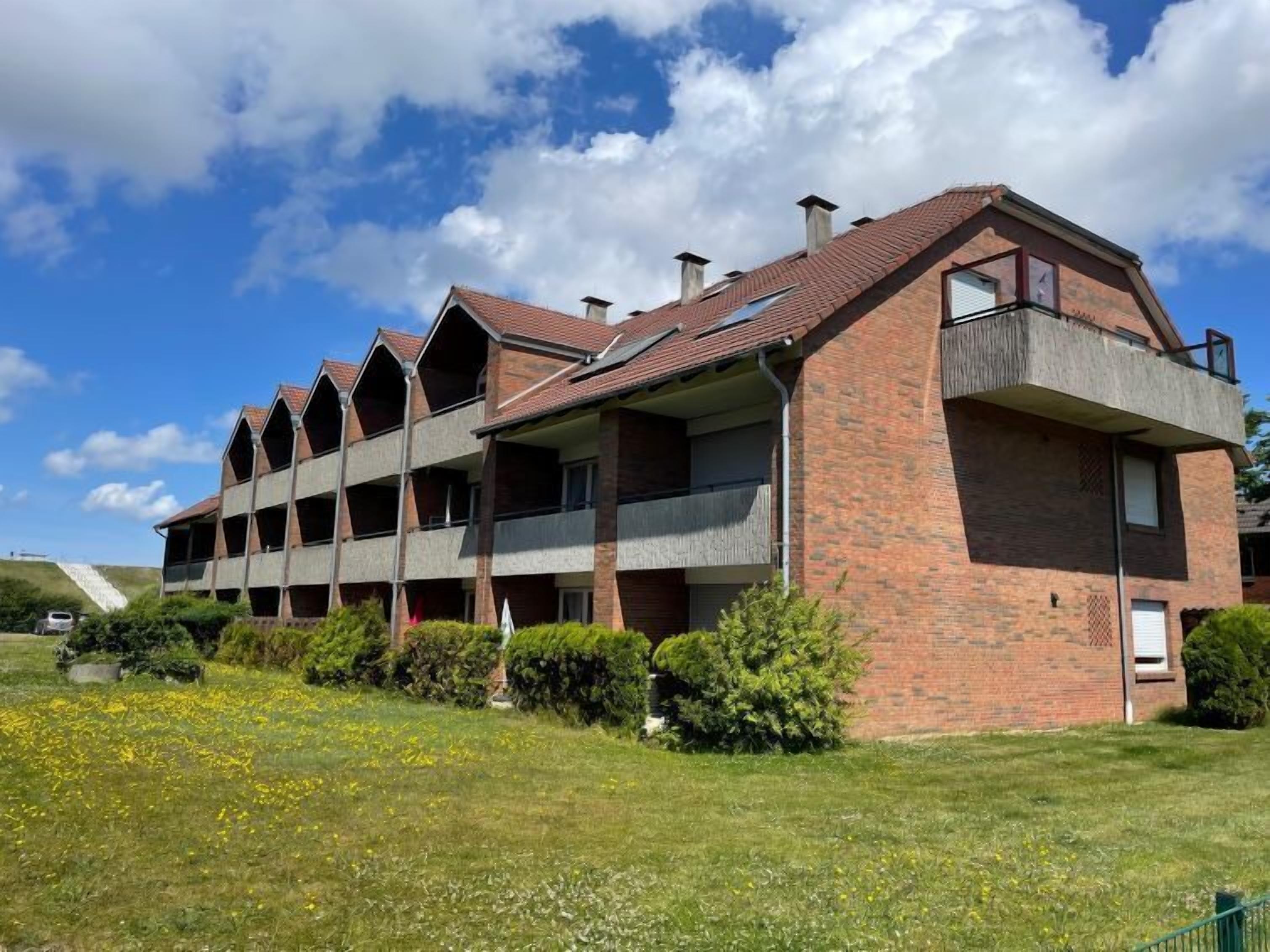 Un edificio de varios pisos con fachada de ladrillo, varios balcones y techo inclinado.