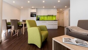 A modern living room with a sofa, a dining area with chairs, a kitchen with white cabinets, and a green backsplash. - Haus Alpenrose by Interhome (Saas-Almagell)