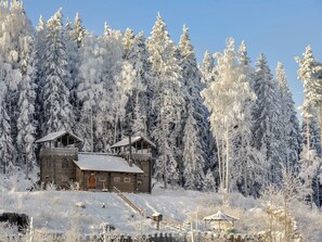 Eine Holzhütte mit geneigtem Dach, umgeben von schneebedeckten Bäumen.