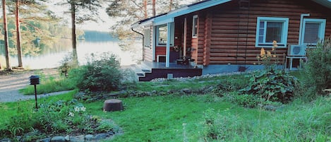 Eine Blockhütte mit Veranda, umgeben von einer natürlichen Landschaft und einem See.