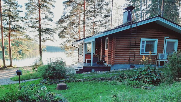 A log cabin with a porch, surrounded by a natural landscape and a lake. - Lomasuvas by Interhome (Tuusniemi)