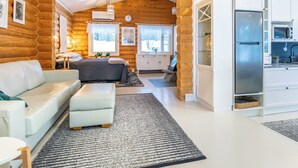 A log cabin interior with a living area, a sofa, a dining table, and a kitchen with a refrigerator. - Lomasuvas by Interhome (Tuusniemi)