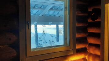 Eine Blockhütte mit einem Fenster, durch das eine verschneite Landschaft zu sehen ist.