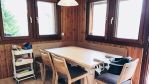 A wooden interior with a large table and four chairs, a white shelf unit, and a ceiling light. - Almenrausch 1. OG Süd-Ost by Interhome (Riederalp)