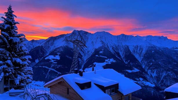 A wooden cabin with a balcony, surrounded by snow-covered mountains and a sunset sky. - Almenrausch 1. OG Süd-Ost by Interhome (Riederalp)