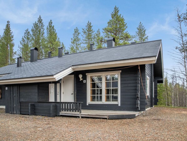A two-story house with a dark exterior, a front porch, and a chimney.