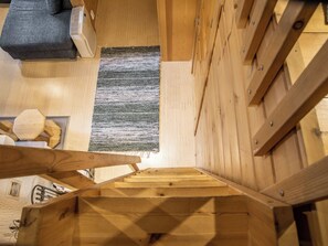 A wooden interior with a visible ceiling, a rug, and a sofa.