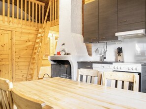 A wooden interior with a kitchen area, including a stove, sink, and wooden chairs.