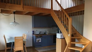 A kitchen with wooden cabinets, a dining table with chairs, and a wooden staircase. - Schwizi's Holiday Apartments by Interhome (Ringgenberg)