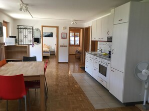 Een koelkast, een magnetron, kookgerei, borden en bestek, eettafels