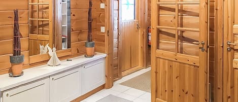 Un interior de madera con una encimera blanca, un espejo y una puerta con paneles de vidrio.