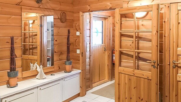 A wooden cabin interior with a large mirror, a wooden door, and a white cabinet. - Metsä-vuosseli rukalumous by Interhome (Kuusamo)