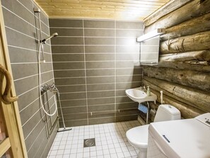 A bathroom with a wooden log wall, a shower with a handheld showerhead, a sink with a soap dispenser, and a toilet. - Ylläsrova b5 / kasku by Interhome (Ylläsjärvi)
