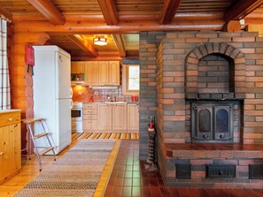 Eine rustikale Küche mit Holzschränken, einem Steinkamin und einem Kühlschrank.