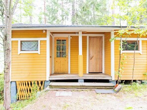 Una pequeña cabaña de madera con un porche, una ventana y una puerta.