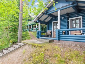Eine Blockhütte mit Veranda, Holzstufen und einer Bank.