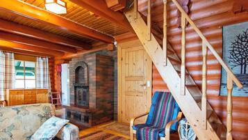 Ein Blockhaus-Interieur mit Kamin, einer Holztreppe und einer gemütlichen Sitzecke.
