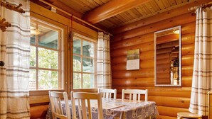 L'intérieur d'un chalet en bois, avec une table à manger, des chaises et un miroir.
