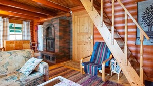 Un intérieur chaleureux de chalet en bois, avec une cheminée, un escalier en bois et des meubles rustiques.