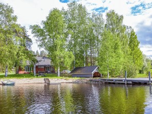 A lakeside cabin with a dock, surrounded by trees.