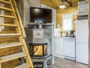 Eine moderne Küche mit Kamin aus Stein, einem Fernseher und einem Geschirrspüler.