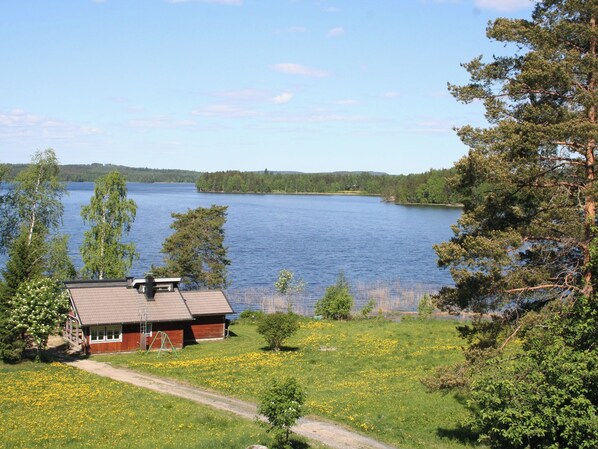 A lakeside cabin with a view of the lake, surrounded by greenery and trees.
