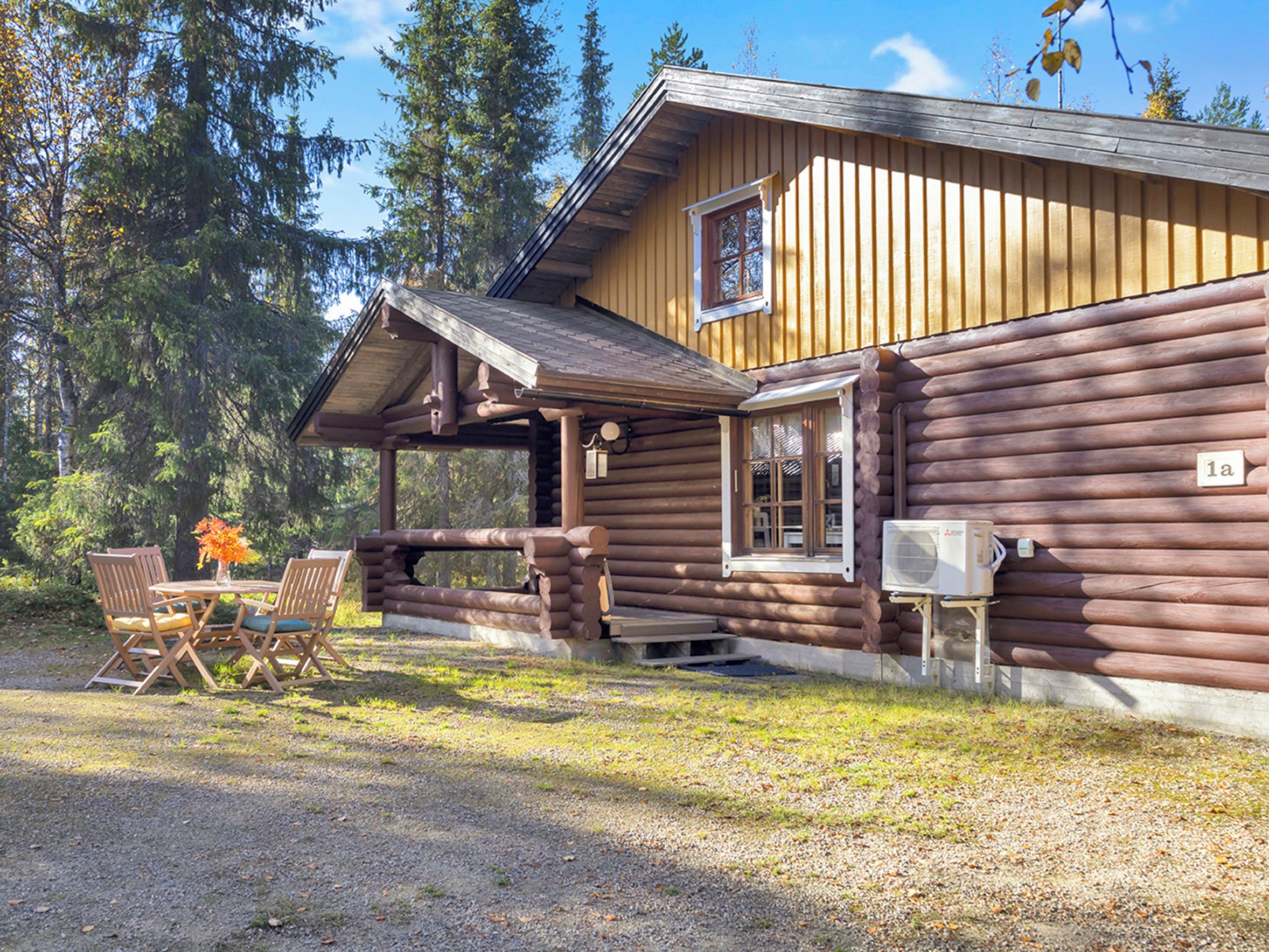 En hytte med veranda, udendørs møbler og et lille bord.