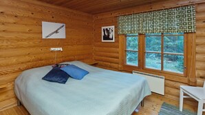 Een houten kamer met een bed, een raam met gordijnen en een afbeelding van een adelaar aan de muur.