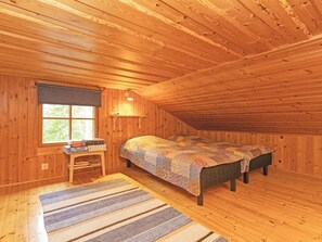 Een gezellige slaapkamer op zolder, met houten wanden en een schuine kap.