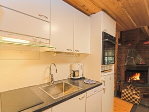 Una cocina compacta con estufa moderna, cafetera y horno empotrado.