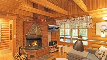 L'intérieur d'un chalet confortable, avec une cheminée, un téléviseur et un canapé.